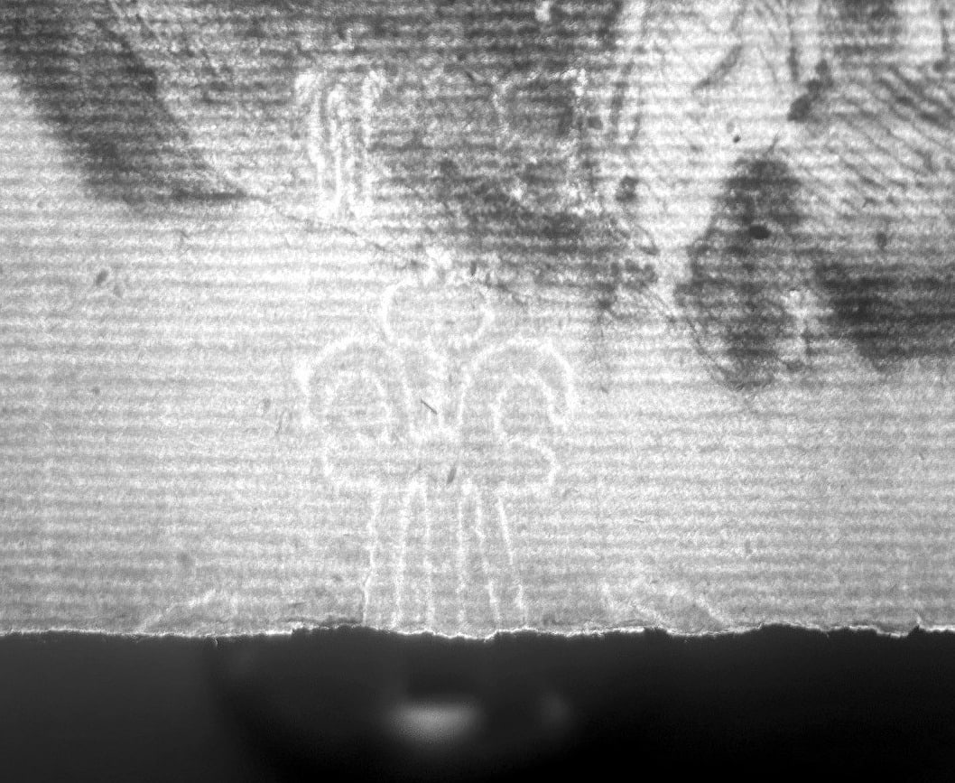 Contrast-enhanced grayscale transmitted-light view of the partial wire figure: a ball element, two symmetric volutes, and straight wires cut by the sheet edge.